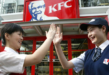 Two KFC staff clap hands to cheer each other outside a KFC restaurant in Shanghai April 20. [Xinhua] 