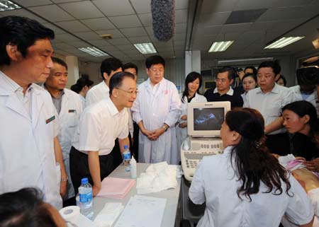 Chinese Premier Wen Jiabao inquires the health condition of a child sickened by tainted milk powder at the ultrasonic scan room of Beijing Children's Hospital in Beijing on Sept. 21, 2008. [Xinhua Photo]