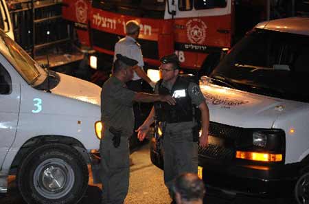 Israeli police officers stand at the scene of an attack in Jerusalem September 22, 2008. A man driving a black BMW plowed into a crowd of people at a busy Jerusalem intersection Monday evening, leaving 19 people hurt, an Israel Police spokesman told Xinhua.