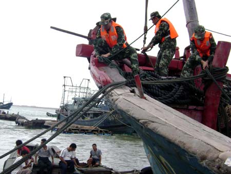 Frontier defense soldiers help fishermen reinforce boats in precaution against Hagupit, the 14th typhoon to affect China this year, in Zhangzhou City, southeast China's Fujian Province, Sept. 23, 2008. Local meteorological station issued a yellow signal for typhoon early Tuesday, warning the central and southern coastal areas of Fujian against the outer rim of Hagupit.