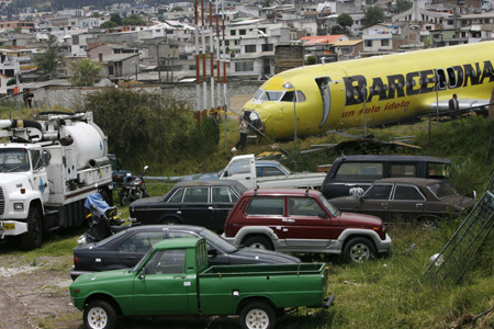 People stand beside a wrecked plane after it skidded off a runway at Mariscal Surce International Airport in Quito September 22, 2008. The plane carrying more than 60 people skidded off a runway and crashed through a brick perimeter wall before stopping near a busy road in Ecuador&apos;s capital on Monday, but no one was seriously hurt. [Agencies via Chinadaily.com.cn]