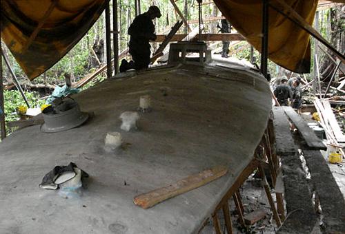 Picture released by the Colombian Police on September 22, 2008 of a Colombian policeman inspecting a home-made submersible in construction in the Municipality of Tumaco, Department on Narino, Colombia. According to authorities, the clandestine shipyard was used to built submersibles for drug traffickers with a capacity to transport up to 4 tons of cocaine through the Pacific Ocean. [Xinhua]
