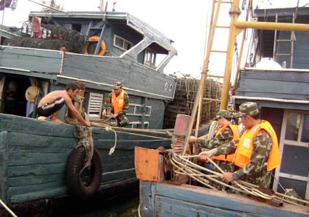 Frontier defense soldiers help fishermen reinforce boats in precaution against Hagupit, the 14th typhoon to affect China this year, in Zhangzhou City, southeast China's Fujian Province, Sept. 23, 2008. Local meteorological station issued a yellow signal for typhoon early Tuesday, warning the central and southern coastal area of Fujian against the outer rim of Hagupit.
