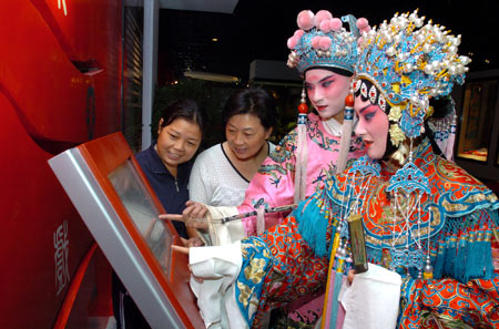 Opera performers search for information on a screen in the Huai'an Drama Museum in Huai'an city, east China's Jiangsu province, Sept. 22, 2008. The museum, featuring vivid introduction on the local drama's origin and development in Huai'an, opened to public on Monday. 