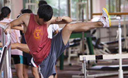 Chinese hurdler Liu Xiang stretches in a training session in Shanghai, Sept. 23, 2008. This is Liu's first public training after he pulled out of the men's 110 meters hurdles because of injuries in Beijing Olympic Games on Aug. 18, 2008.