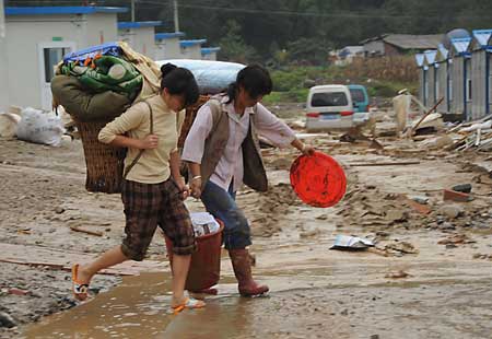 People with their belongings flee their homes after a landslide caused by torrential rain in Leigu township, Beichuan counry of southwest China's Sichuan Province on Sept. 24, 2008. [Xinhua Photo]