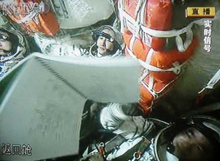 Chinese astronauts are seen in the cabin of the Shenzhou VII spacecraft in this frame grab taken on September 25, 2008. One of them will walk in space about 343 km above the Earth on Saturday. [cctv.com]