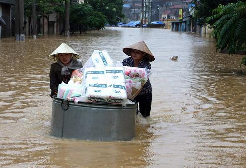 Residents wade on a flooded street as they move their belongings to a safer place in the northern town of Lang Son on September 26, 2008. The death toll from floods in northern Vietnam triggered by Typhoon Hagupit has risen to at least 25 while four others are missing, disaster officials said September 27. [Xinhua]