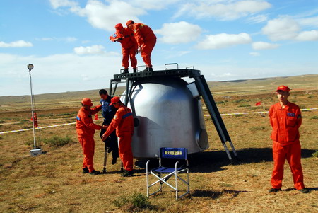 Search and rescue staff -- who will assist the three astronauts onboard the Shenzhou VII spacecraft out of the returning module --practice during a simulated drill on the Amugulang prairies in the middle ofNorth China&apos;s Inner Mongolia Autonomous Region, September 25, 2008. The spacecraft will return around 5 pm today after a three-day mission in space. [CFP]