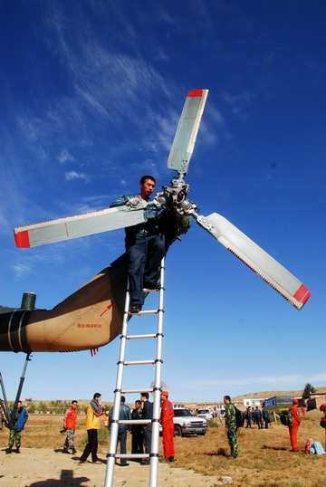 A helicopter crewmember cleans the rotor blades on the prairies of North China&apos;s Inner Mongolia Autonomous Region, September 25, 2008, preparing for the research and rescue mission ahead of the return of the Shenzhou VII spacecraft Sunday afternoon. The spacecraft will return around 5 pm today after a three-day mission in space. [CFP]