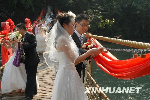 New couples lock the one-heart locks together at a group wedding ceremony in a Shenzhen folk village on Monday, September 29, 2008. [Xinhua]