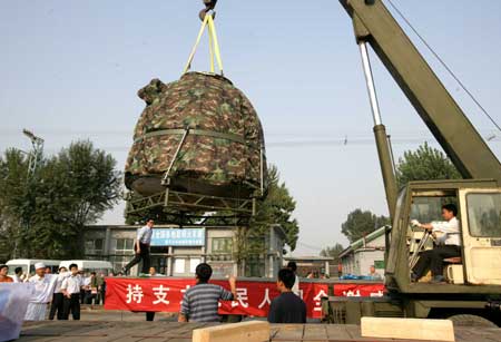 The re-entry module of China's Shenzhou VII spacecraft is lifted onto a truck at Beijing's Changping railway station Sept. 30, 2008. The module was shipped to Beijing Tuesday afternoon, two days after its safe landing in northern China's Inner Mongolia. [Zha Chunming/Xinhua]