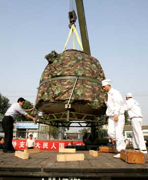 The re-entry module of China's Shenzhou VII spacecraft is lifted onto a truck at Beijing's Changping railway station Sept. 30, 2008. The module was shipped to Beijing Tuesday afternoon, two days after its safe landing in northern China's Inner Mongolia. [Zha Chunming/Xinhua]