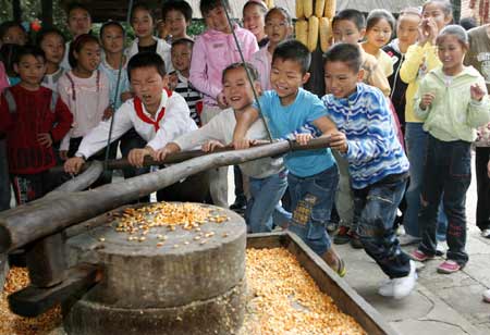 Students try to grind the corns at a park in Nantong, east China's Jiangsu Pronvince, Sept. 30, 2008. Students of Hetao primary school visited a farm park in the city to experience the farmers' life by learning some simple agricultural works. [Xinhua] 