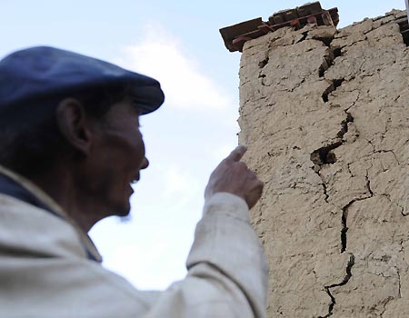 A local farmer checks the damaged building in Gedar Township of Damxung County in southwest China's Tibet Autonomous Region, Oct. 6, 2008. [Xinhua] 