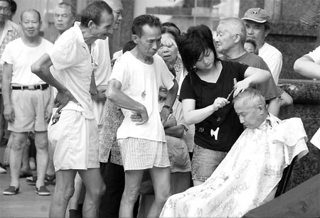 Residents wait for their haircuts in Nanjing Road, Shanghai, on Aug 20. People get free haircuts and repairs of small items such as umbrellas, radios and watches on the 20th of every month, in line with a 20-year-old service for the community. [Photo: CFP] 