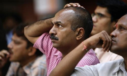 Indian investors watch share prices on a digital stock ticker