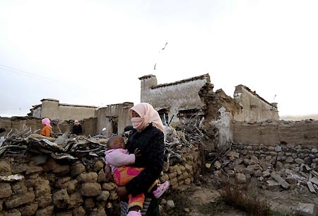 A woman with her child walks past collapsed buildings in Gedar Township of Damxung County in southwest China&apos;s Tibet Autonomous Region, Oct. 6, 2008. At least nine people were killed in a 6.6-magnitude earthquake that jolted Damxung County near Lhasa at 4:30 p.m. Monday, the rescue headquarters confirmed early Tuesday morning. 