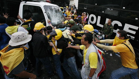 Demonstrators attempt to over turn a police vehicle parked outside Parliament in Bangkok October 7, 2008. Thai riot police clashed with protesters in the capital on Tuesday, injuring more than 380 people. [Agencies]