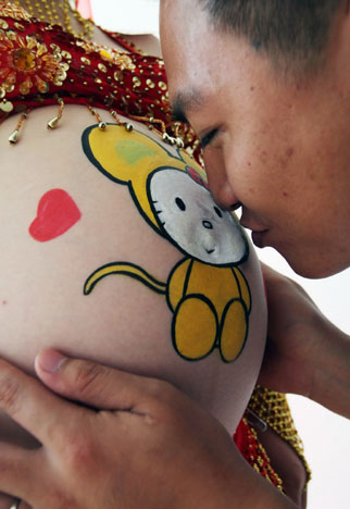 A father-to-be kisses his wife&apos;s painted belly at a body-painting competition for pregnant women in Haikou, South China&apos;s Hainan Province on October 8, 2008. [Photo: CFP]
