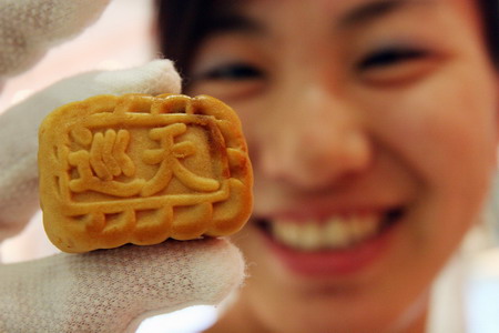 An employee shows a moon cake for Chinese astronauts during their space mission during a space food show in a collectibles shop in Beijing October 7, 2008. [CFP] 