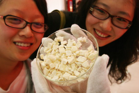 Two young women show interest in a small plate of reconstituted dried fruit for Chinese astronauts during a space food show in a collectibles shop in Beijing, October 7, 2008. [CFP] 