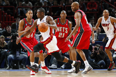 Miami Heat guard Dwyane Wade (2nd L) drives the ball against against New Jersey Nets Devin Harris (L), Bobby Simmons (3rd L) and Vince Carter (R) during the first quarter of their NBA pre-season basketball game in Paris October 9, 2008.[