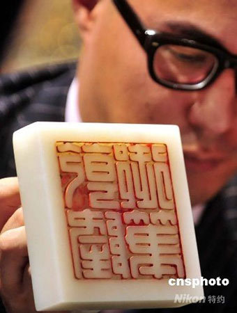 A staff member shows off the 'Qianlong yubi', an imperial white jade seal, to reporters during a media preview on August 26, 2008. [Photo: cnsphoto]