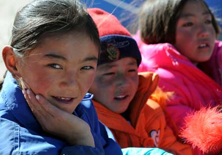 Tibetan school girl smiles while watching the performances at a Primary School of Gedar Township in Damxung County, an outer county of Lhasa, capital of southwest China's Tibet Autonomous Region, Oct. 10, 2008. [Xinhua]