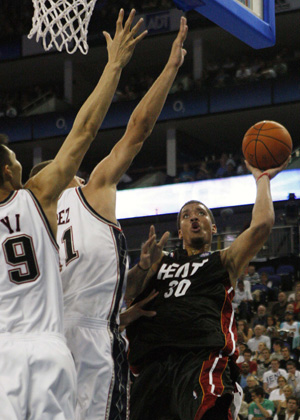 Miami Heat's Michael Beasley (R) shoots over New Jersey Nets' Yi JianLian (L) and Brook Lopez during the first half of their NBA pre-season basketball game in London Oct. 12, 2008. [Xinhua/Reuters]