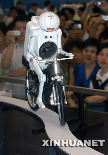 A robot riding a bicycle crosses an 'S'-shaped bridge at the tenth China Hi-Tech Fair held in Shenzhen, Guangdong Province on Sunday, October 12, 2008. The robot was produced by Japanese manufacturers and is outfitted with ultrasonic sensors, gyro sensors and vibration sensors. The sensors transmit signals to the computer, to easily control the robot's speed and direction. [Photo: Xinhua]