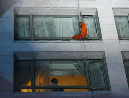 French 'Spiderman' Alain Robert waves during his climb on the facade of the InterContinental Hotel Phoenicia while a guest watches him in Beirut October 11, 2008.