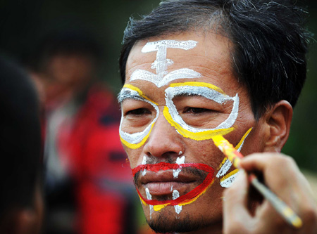 A performer is helped drawing paintings on his face to imitate tiger during the traditional Nuo ritual to exorcise evil spirits and pray for happiness in Shuangbai county, Yi Autonomous Prefecture of Chuxiong, southwest China's Yunnan Province, Oct. 10, 2008. The whole ritual procedure, with different kinds of dances as its main part, is the most ancient and well-preserved ritual for ethnic Yi people. [Xinhua]