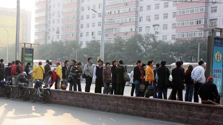  People wait at a bus stop in Beijing, capital of China, Oct. 13, 2008. [Xinhua]
