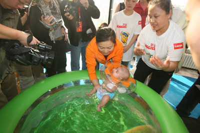 A mother helps her baby prepare for the swimming competition. Huggies, a famous baby care brand, joined the China Youth Concern Committee to hold this swimming competition to promote W&I (Water and Intelligence), a scientific way of nurturing kids. The event concluded on Monday in Beijing. [Photo: sohu.com] 