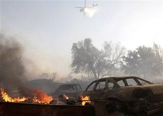 A helicopter drops water on burning mobile homes and cars that have burned from a wind driven brush fire in Los Angeles on Monday, Oct. 13, 2008.[Dan Steinberg/AP Photo] 