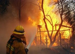 A firefighter tries to put out the fire on a home engulfed in flames just west of Porter Ranch in Los Angeles on Monday Oct. 13, 2008. [Mike Meadows/AP Photo] 