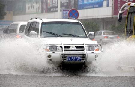 A vehicle trudges its way through the waterlogged street in Haikou, capital of south China's Hainan Province, Oct. 14, 2008. Monsoon rain hit the island in recent days flooding 12 cities and counties and causing two dead in the region. [Photo: Xinhua Photo]