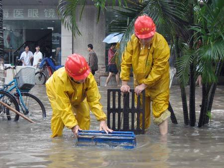 Two plumbers work on the waterlogged street in Haikou, capital of south China's Hainan Province, Oct. 14, 2008. [Photo: Xinhua]