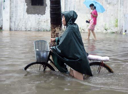 A woman trudges her way through the waterlogged street in Haikou, capital city of south China's Hainan Province, Oct. 14, 2008. [Photo: Xinhua]