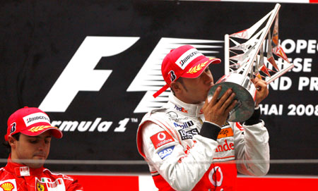 Mclaren-Mercedes team's Lewis Hamilton (R) of Britain kisses the champion trophy after winning the F1 Chinese Grand Prix at the Shanghai International Circuit in Shanghai, east China, on Oct. 19, 2008. [Fan Jun/Xinhua]