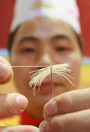 Li Hongkai, a chef from Zigong City in southwestern China&apos;s Sichuan Province, threads a needle with more than 30 handmade noodles in Beijing on Saturday at the 18th China&apos;s Chef Festival, which attracted chefs from 30 provinces and 65 countries and regions. 