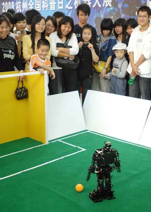 Visitors look at a robot which can play football during a robot expo in Hangzhou, East China&apos;s Zhejiang Province, October 18, 2008. More than 10 kinds of robots are exhibited at this expo. [Xinhua]