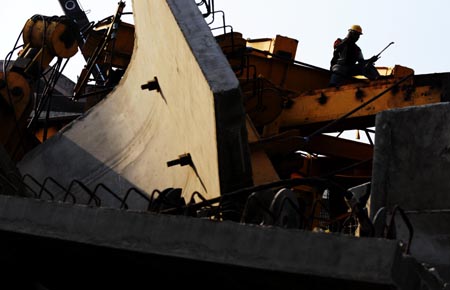 A rescue worker clears up a collapsed under-construction metro line flyover in New Delhi, capital of India, on Oct. 19, 2008. The flyover collapesd on Sunday killing four people and leaving more than 20 injured. (Xinhua/Wang Ye) 