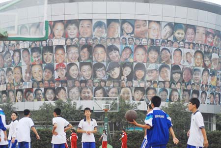 Students exercise next to a wall of smiling faces in Nanjing, Jiangsu Province October 20, 2008. The wall, 10 meters high and 40 meters long, has more than 300 pictures of smiling faces, all students of the middle school. The school hoped to create a light and harmonious environment for the students. [CFP]