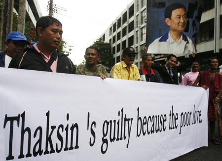 Supporters of Former Prime Minister Thaksin Shinawatra hold a banner and his portrait outside the Supreme Court in Bangkok on October 21, 2008. Thailand's Supreme Court ruled on Tuesday that former prime minister Thaksin Shinawatra had violated a conflict-of-interest law while in office and sentenced him to two years in prison.