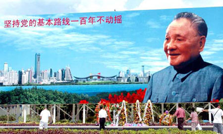 People stroll before a portrait of the late leader Deng Xiaoping, architect of China's reform and opening up, in a square in Shenzhen, Guangdong Province in this file photo