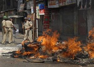 Policemen stand guard besides material from a shop set afire by supporters of hard-line Maharashtra Reconstruction Party in Kalyan, near Mumbai, India, Wednesday, Oct. 22, 2008.[AP Photo] 