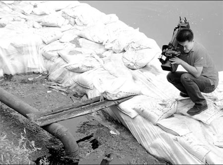 A news cameraman films at one of the sources of pollution near Yangzonghai Lake yesterday. (Photo: Xinhua)