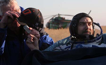 Ground crew members helps U.S. space tourist Richard Garriott shortly after the landing of the Russian Soyuz space capsule near Arkalyk, in north-central Kazakhstan Friday, Oct. 24, 2008. A Soyuz capsule carrying a Russian-American crew has touched down on target in Kazakhstan after a descent from the international space station, safely delivering the first two men to follow their fathers into space. [Xinhua/AFP]